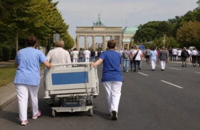 Реформа ухода в Германии: работники везут больничную кровать в Берлин